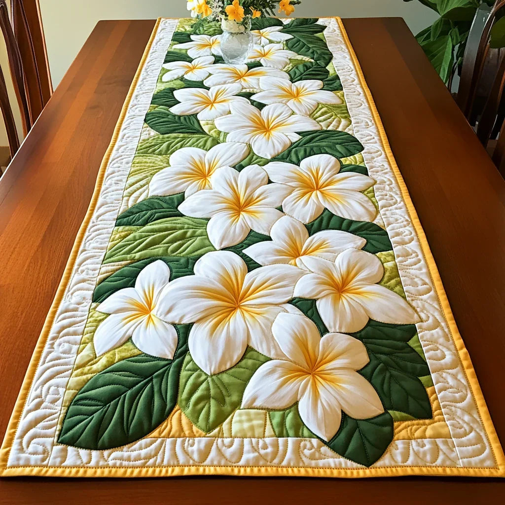 Quilted table runner with white frangipani flowers, yellow centers, green leaves, border trim