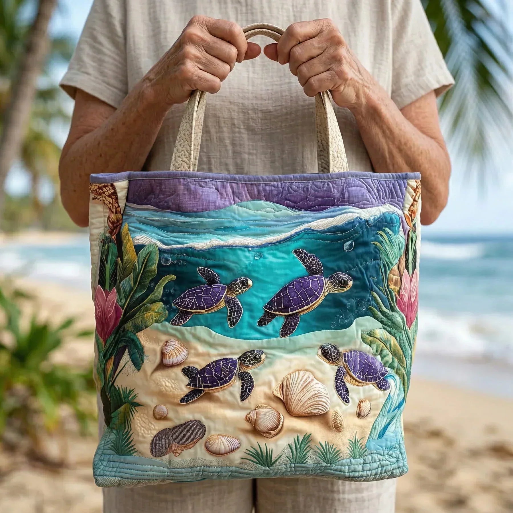 Handheld tote bag featuring embroidered sea turtles and shells with two fabric handles.