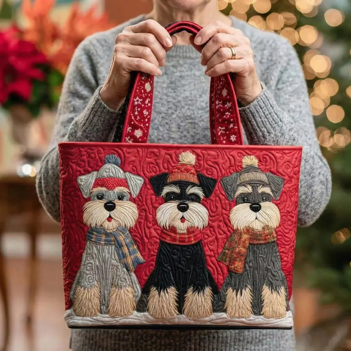 Red embroidered tote bag with three puppy faces, held by a person with knitted sleeves